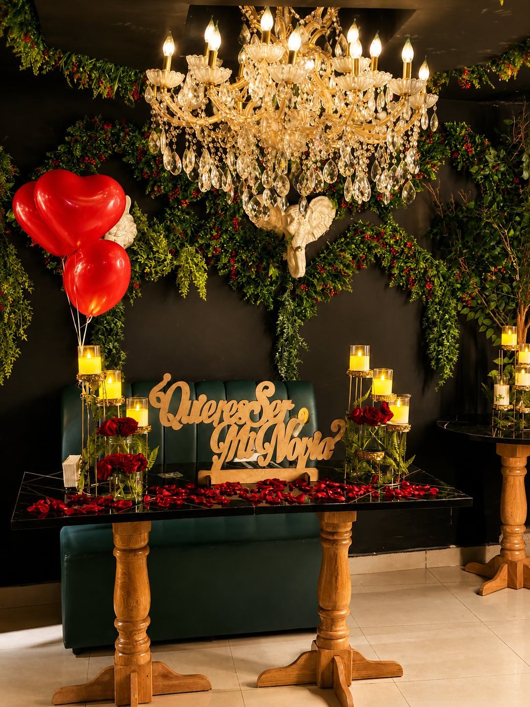Mesa decorada para pedida de noviazgo con pétalos, velas y globos de corazón