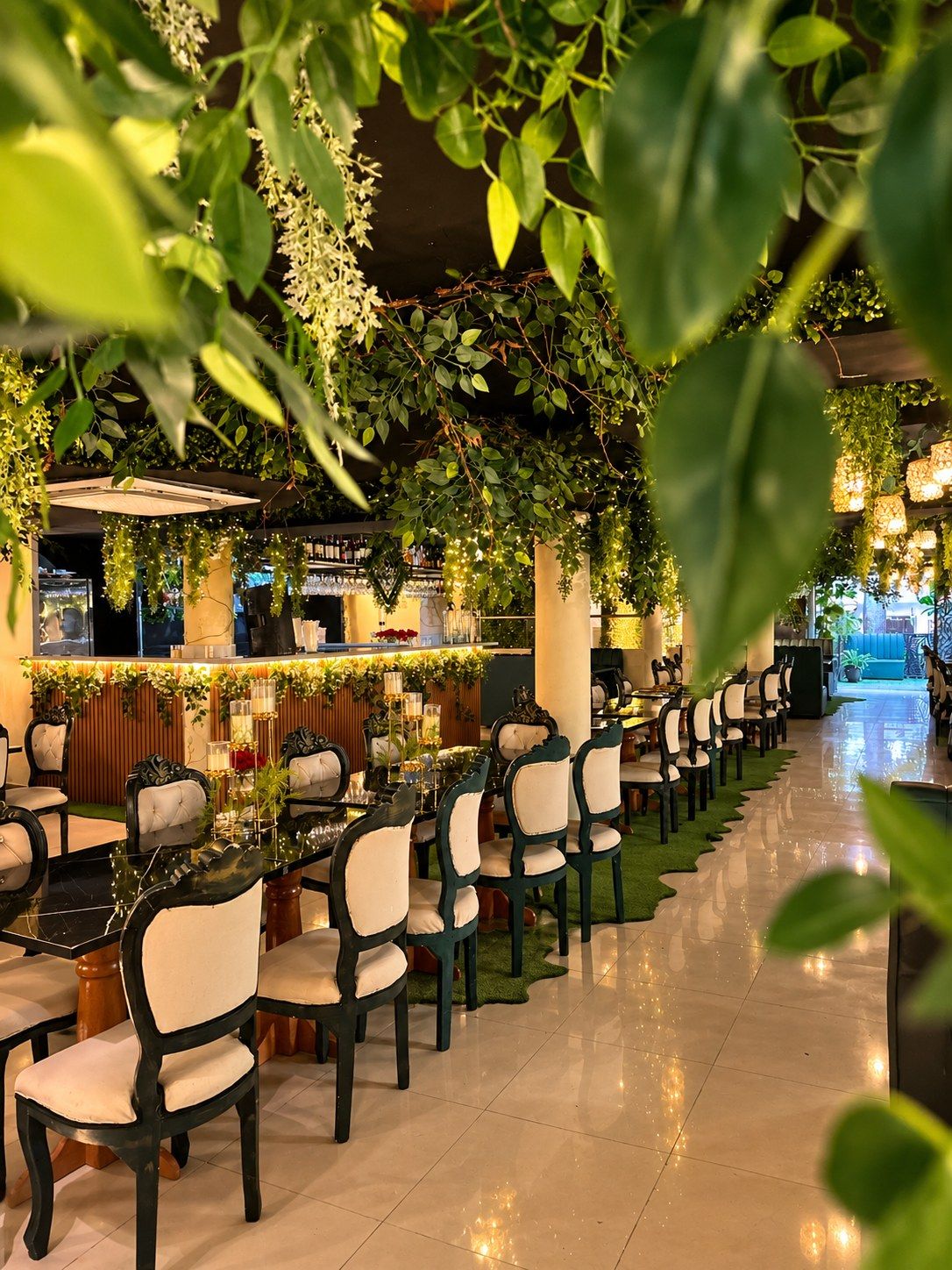Salón principal de Almonte Restobar visto entre hojas, con sillas blancas